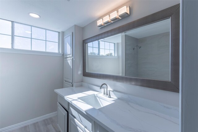 bathroom with hardwood / wood-style floors, vanity, and tiled shower