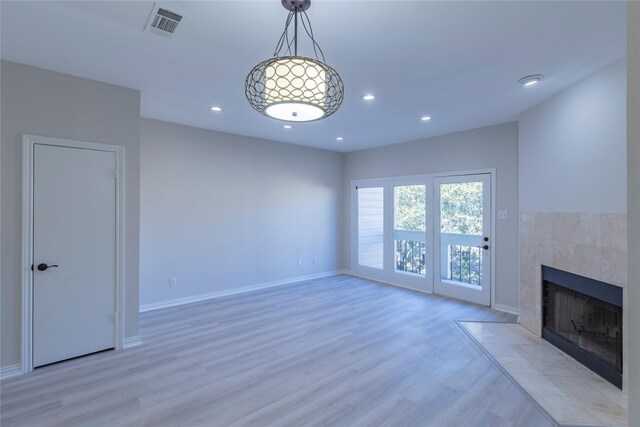 unfurnished living room with a tile fireplace and light wood-type flooring