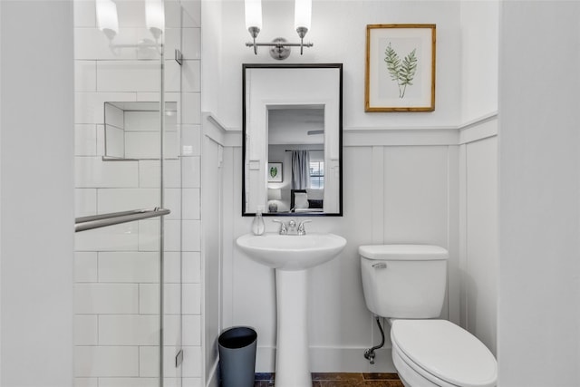 bathroom featuring toilet, a shower with shower door, and sink