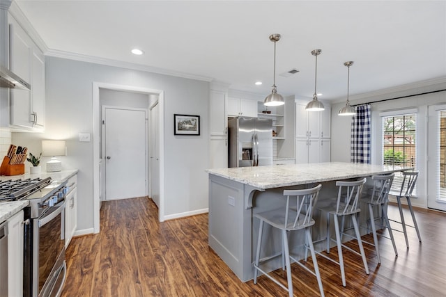 kitchen with white cabinets, appliances with stainless steel finishes, a center island, and pendant lighting