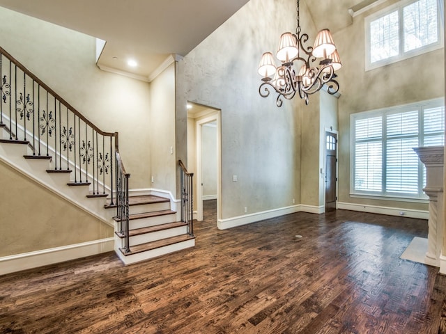 unfurnished dining area featuring a notable chandelier, dark hardwood / wood-style flooring, a towering ceiling, and a wealth of natural light