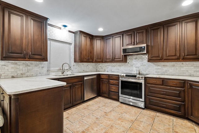 kitchen with tasteful backsplash, light stone countertops, sink, and appliances with stainless steel finishes