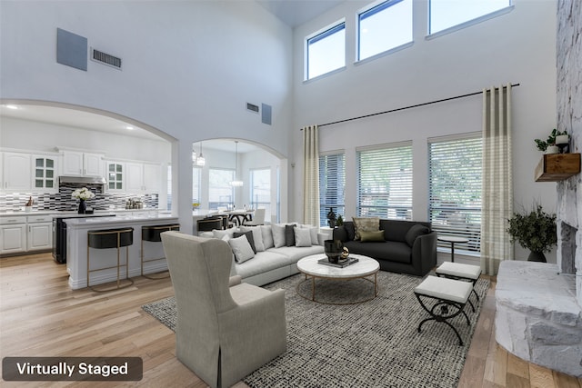 living room with a chandelier, a high ceiling, and light wood-type flooring