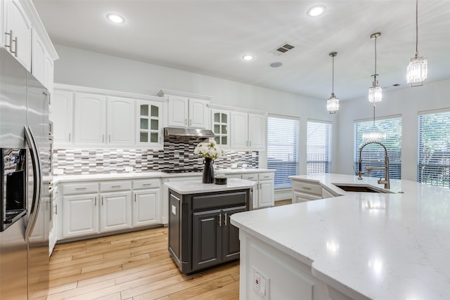 kitchen with stainless steel refrigerator with ice dispenser, decorative light fixtures, white cabinetry, and sink