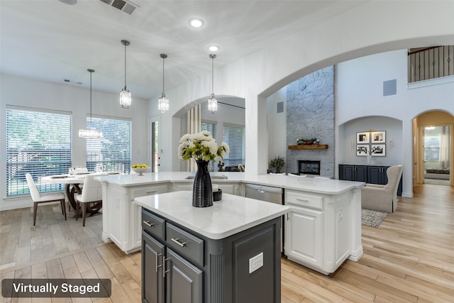 kitchen featuring white cabinetry, a fireplace, a kitchen island, and light hardwood / wood-style floors