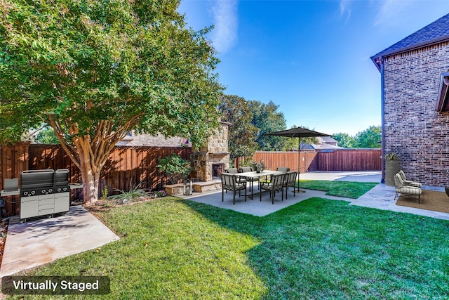 view of yard featuring an outdoor stone fireplace and a patio area