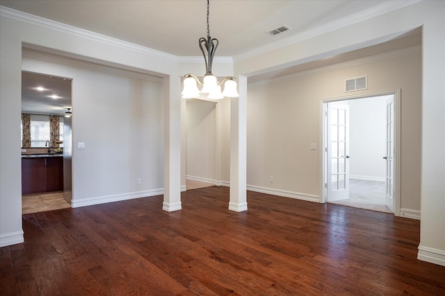 unfurnished dining area featuring ornate columns, ornamental molding, and dark wood-type flooring