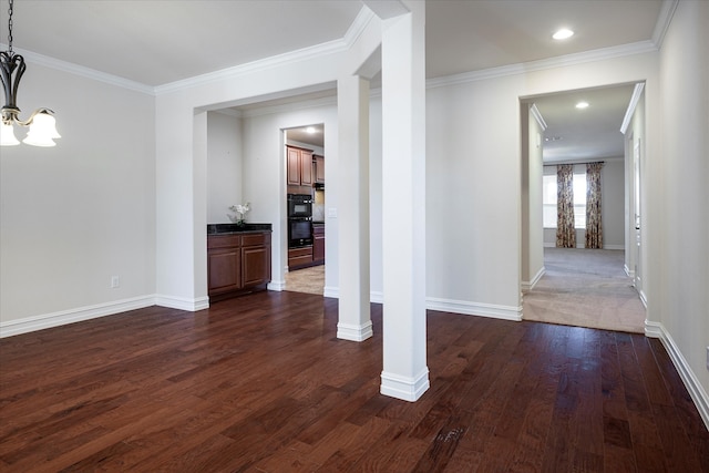 unfurnished dining area with dark wood-type flooring, a notable chandelier, ornamental molding, and ornate columns