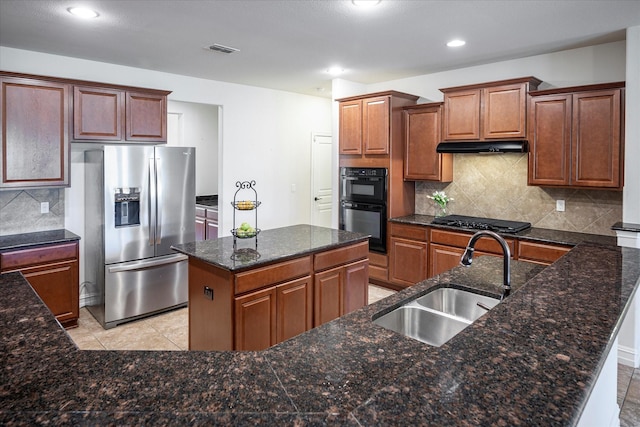 kitchen with sink, decorative backsplash, light tile patterned floors, black appliances, and a center island with sink