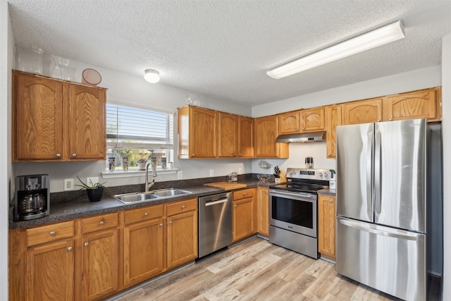 kitchen featuring sink, stainless steel appliances, a textured ceiling, and light wood-type flooring