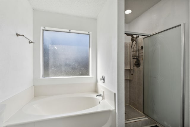 bathroom featuring shower with separate bathtub, a textured ceiling, and a healthy amount of sunlight