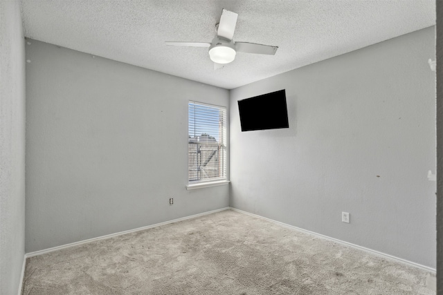 spare room featuring a textured ceiling, light colored carpet, and ceiling fan