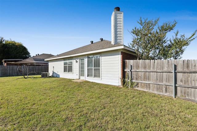 back of property featuring central AC unit and a yard