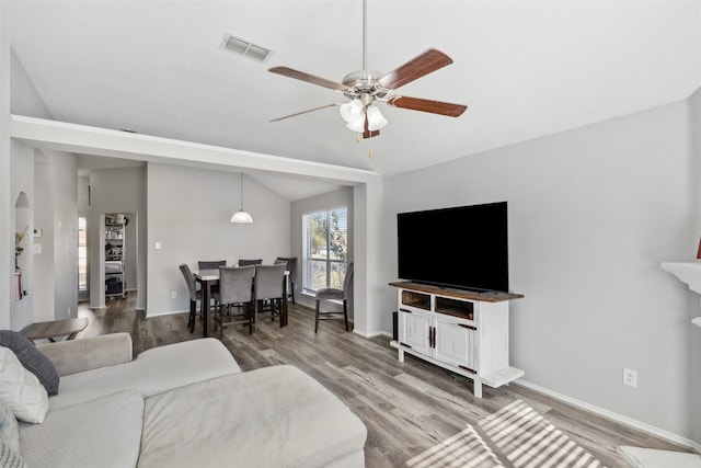 living room with hardwood / wood-style floors, ceiling fan, and vaulted ceiling