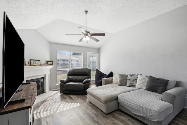 living room with wood-type flooring, a textured ceiling, ceiling fan, and lofted ceiling