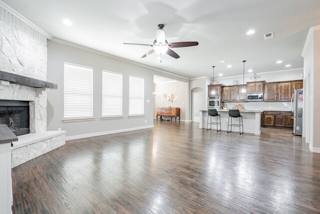 kitchen featuring pendant lighting, dark hardwood / wood-style floors, light stone countertops, an island with sink, and stainless steel appliances