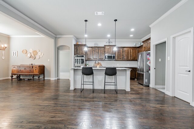 kitchen featuring a kitchen island with sink, dark hardwood / wood-style floors, decorative backsplash, dark brown cabinets, and appliances with stainless steel finishes