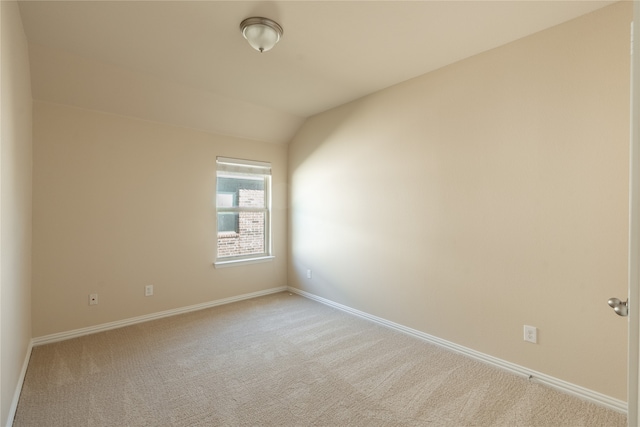 carpeted spare room with lofted ceiling