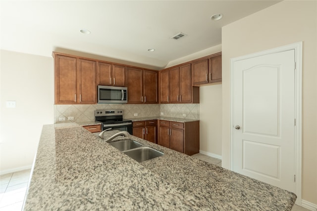 kitchen with decorative backsplash, light stone counters, sink, and stainless steel appliances