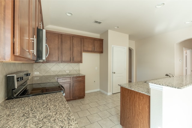 kitchen featuring appliances with stainless steel finishes, tasteful backsplash, and light stone counters