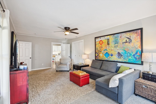 carpeted living room with ornamental molding and ceiling fan