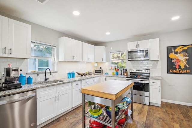 kitchen with sink, white cabinetry, light stone counters, dark hardwood / wood-style flooring, and stainless steel appliances