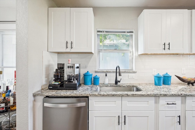 kitchen featuring white cabinetry, stainless steel dishwasher, light stone countertops, and sink