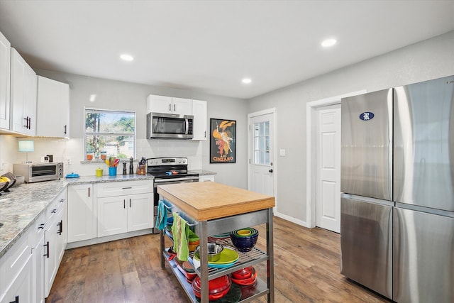 kitchen featuring white cabinetry, appliances with stainless steel finishes, dark hardwood / wood-style flooring, and light stone counters