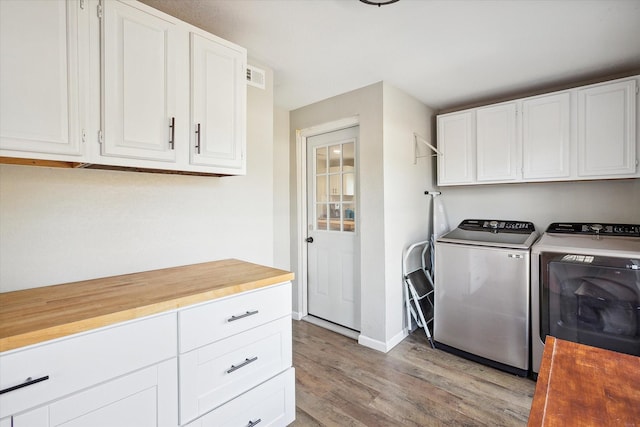 laundry area with cabinets, separate washer and dryer, and light hardwood / wood-style floors