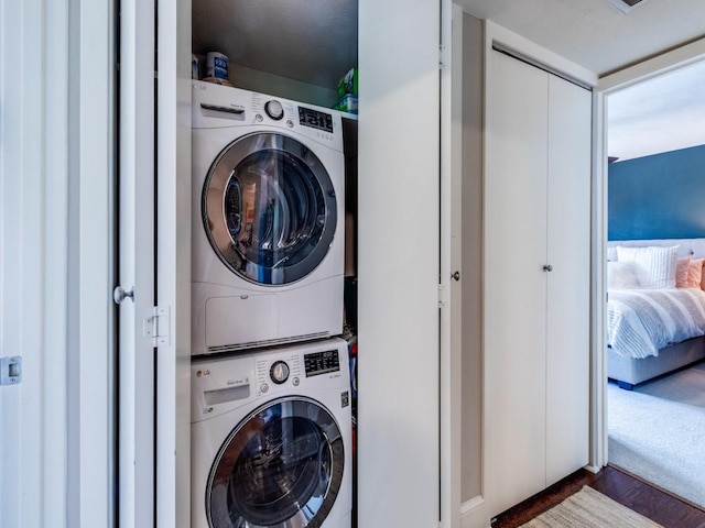 laundry room with stacked washer / drying machine and dark hardwood / wood-style floors