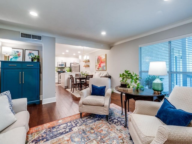 living room with crown molding, dark wood-type flooring, and a notable chandelier