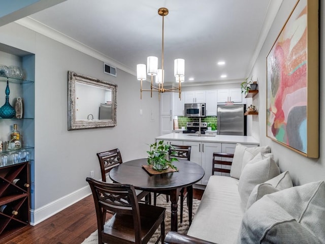 dining space featuring sink, dark hardwood / wood-style floors, crown molding, and a notable chandelier