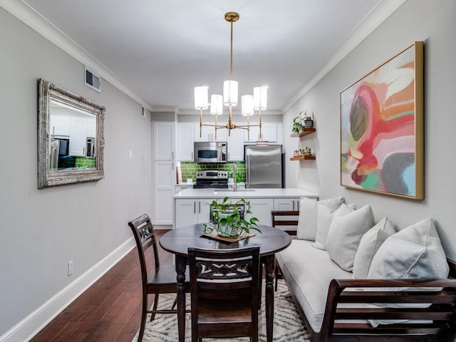 dining room with sink, dark hardwood / wood-style flooring, crown molding, and an inviting chandelier