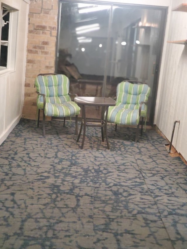 sitting room featuring dark carpet and brick wall