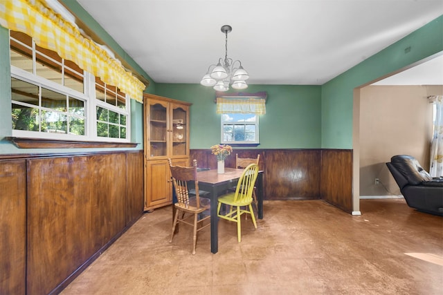 dining space featuring wood walls and a notable chandelier