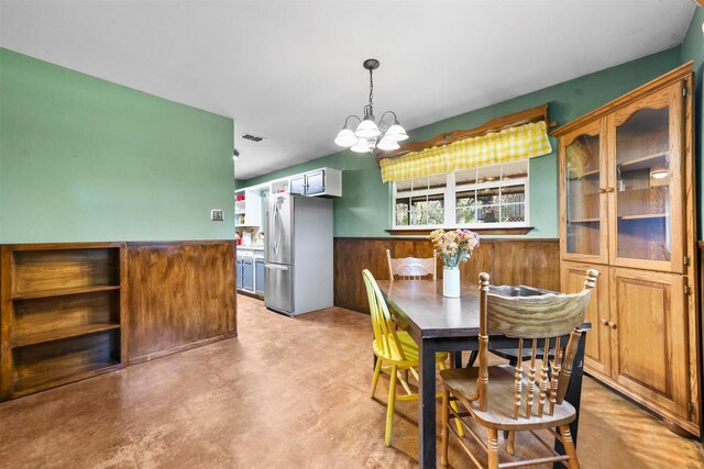 dining space with a chandelier and wooden walls