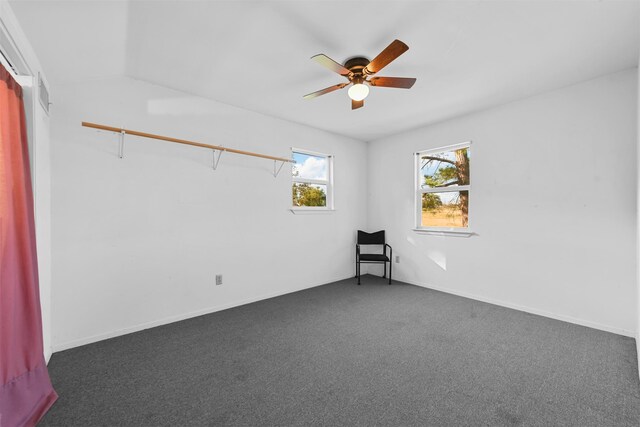 unfurnished room with vaulted ceiling, dark carpet, and ceiling fan