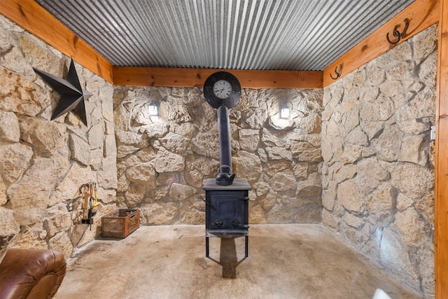 room details featuring concrete flooring, beam ceiling, a wood stove, and wood ceiling