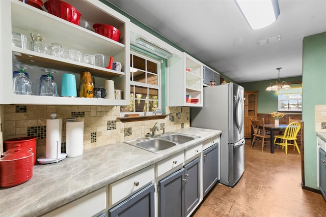 kitchen featuring pendant lighting, gray cabinetry, sink, stainless steel fridge, and tasteful backsplash