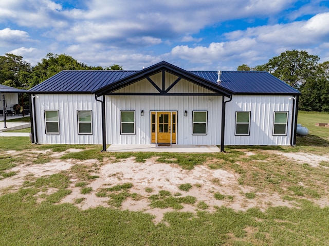 view of front facade with metal roof, a patio, and board and batten siding