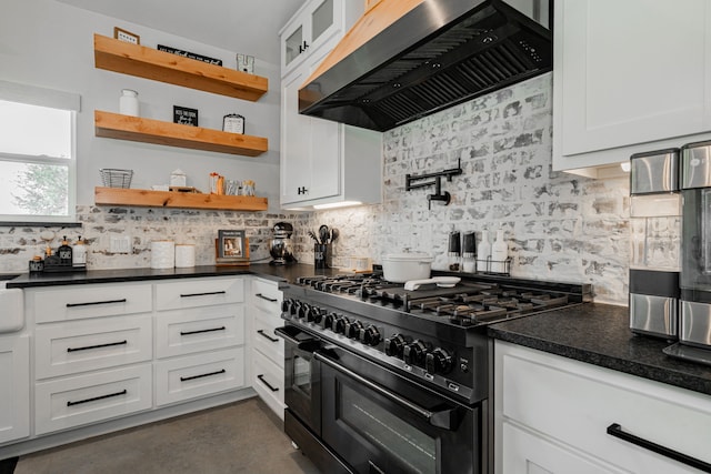 kitchen featuring ventilation hood, dark countertops, gas range oven, and white cabinetry