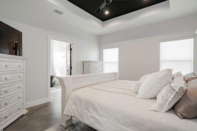 bedroom featuring visible vents, baseboards, concrete flooring, a tray ceiling, and recessed lighting