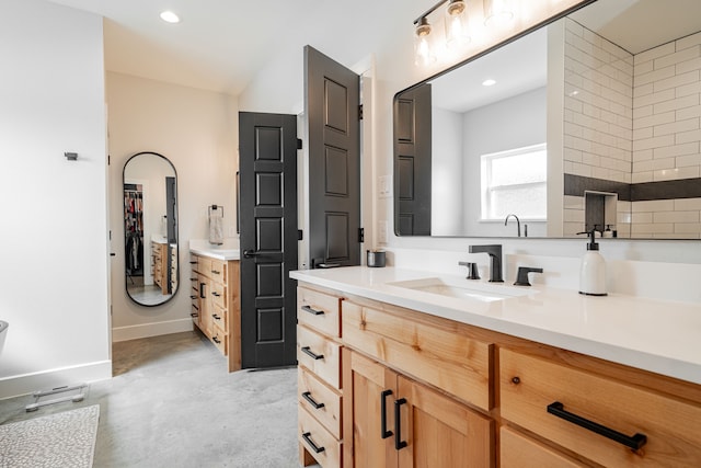 bathroom with vanity, baseboards, recessed lighting, a spacious closet, and concrete flooring