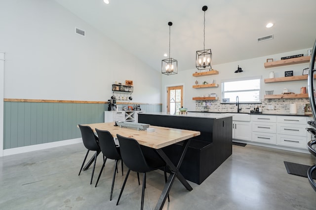 kitchen featuring visible vents, open shelves, a center island, white cabinetry, and concrete floors