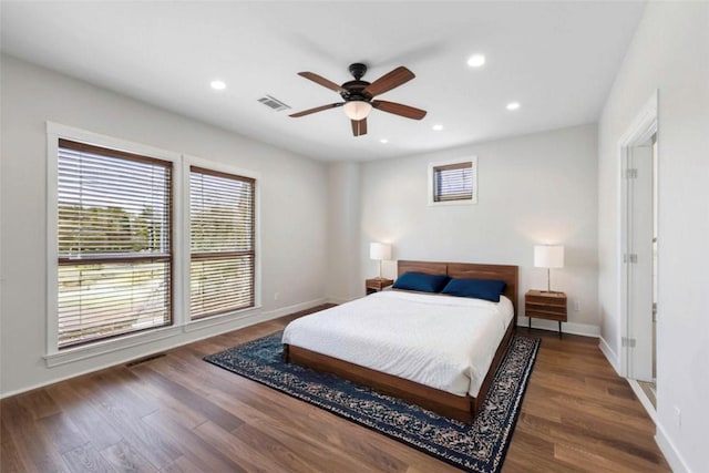 bedroom featuring ceiling fan, dark hardwood / wood-style floors, and multiple windows