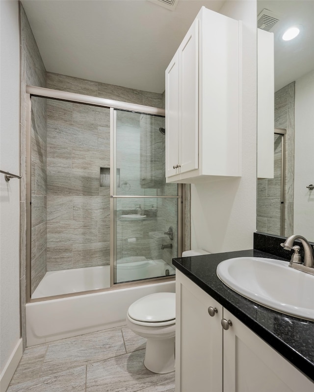 full bathroom featuring vanity, bath / shower combo with glass door, and toilet