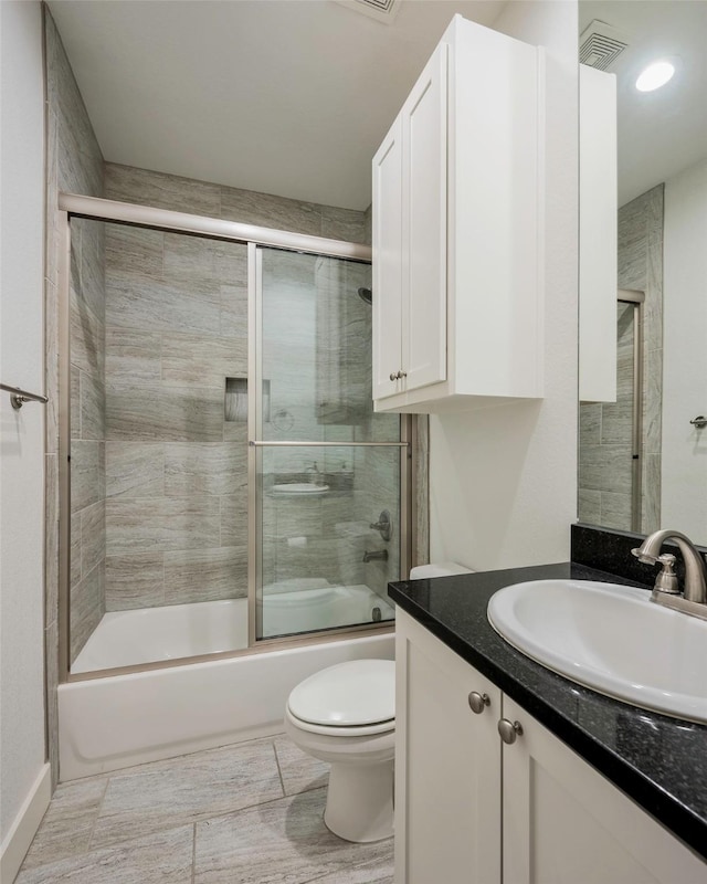 full bathroom featuring vanity, toilet, and combined bath / shower with glass door