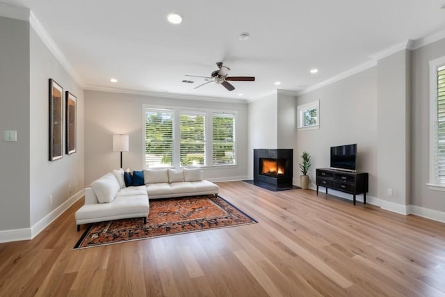 living room featuring ceiling fan, a multi sided fireplace, ornamental molding, and light hardwood / wood-style floors