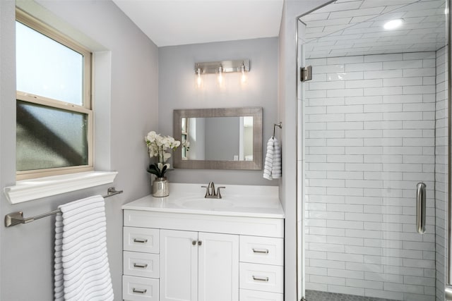 bathroom featuring a shower with door and vanity