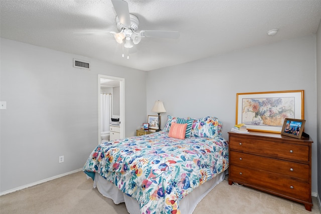 carpeted bedroom with ceiling fan, ensuite bathroom, and a textured ceiling